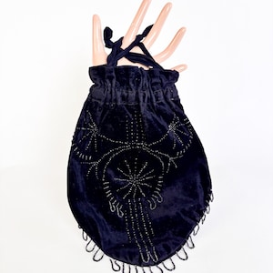 Può includere: Una borsa con coulisse in velluto blu navy scuro con abbellimenti di perline. La borsa presenta un design a forma di stella e frange di perline lungo il bordo inferiore. Il cordoncino è realizzato in tessuto blu navy abbinato.