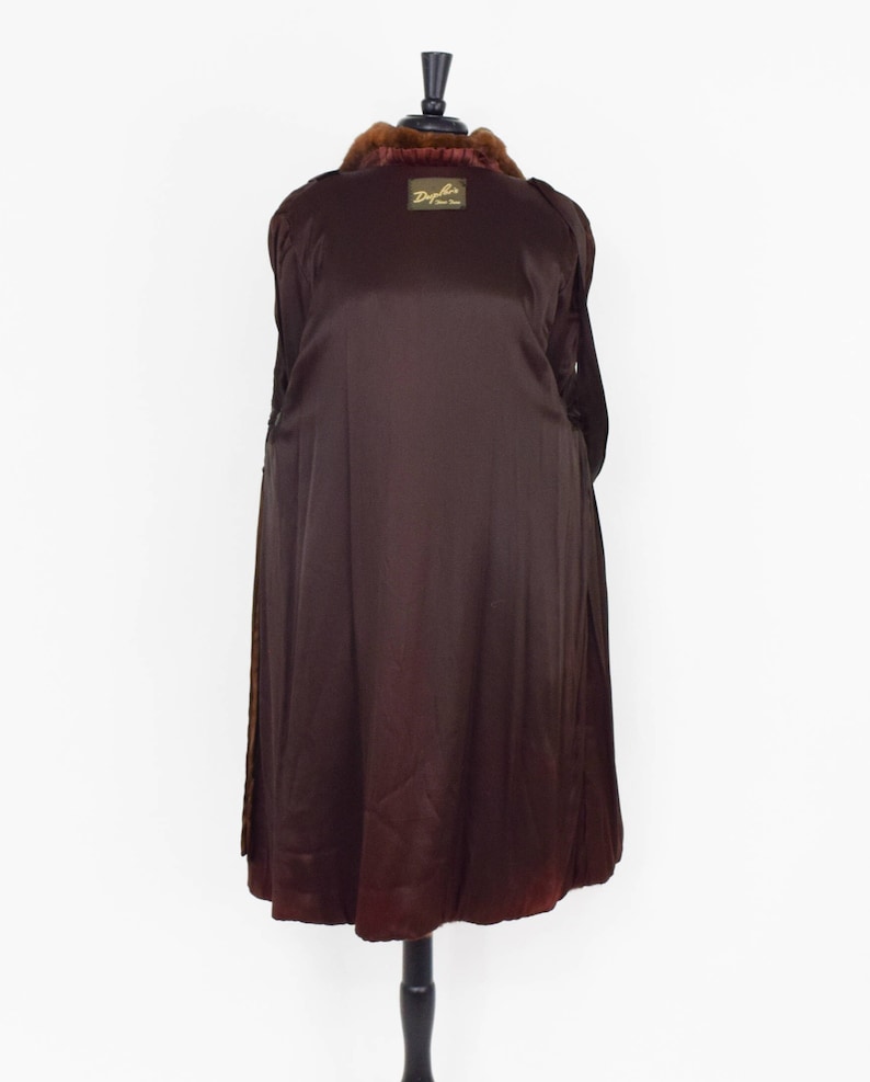 May include: A brown fur coat with a brown satin lining. The coat has a label that reads "Dyfur Fine Furs".