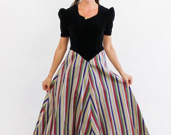 May include: A black velvet bodice with puffed sleeves and a striped skirt in shades of red, yellow, blue, and green. The skirt is a full-length, A-line style.