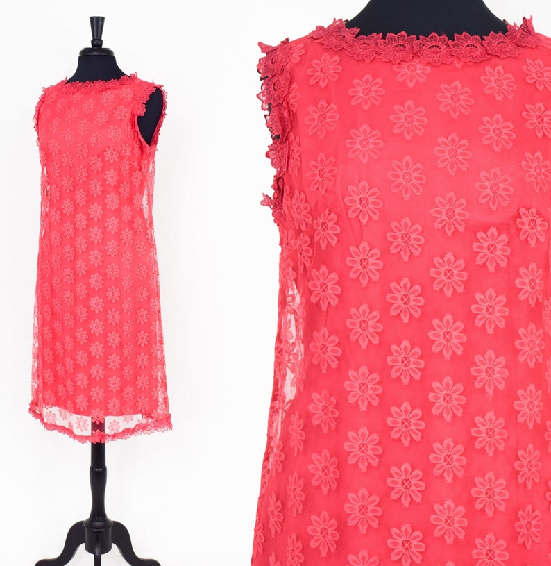 May include: A sleeveless, coral-colored dress with a floral pattern and a scalloped lace trim around the neckline and hem.