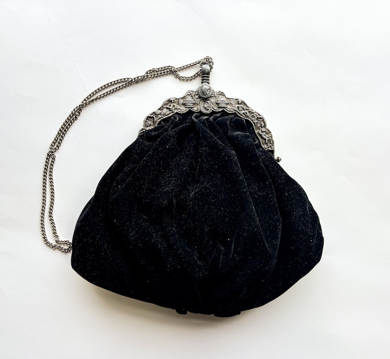 May include: A black velvet evening bag with a silver chain strap and ornate silver clasp.