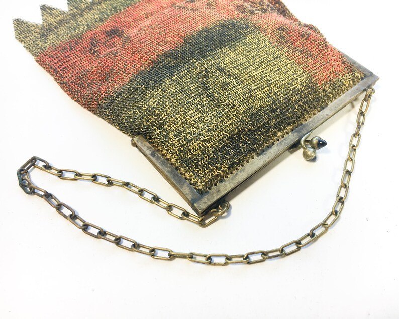 K&ouml;nnte beinhalten: Eine Vintage-Mesh-Handtasche mit einer Kettenkette. Die Tasche ist aus feinem Metallgewebe gefertigt und hat eine rot-schwarz-goldene Farbgebung.