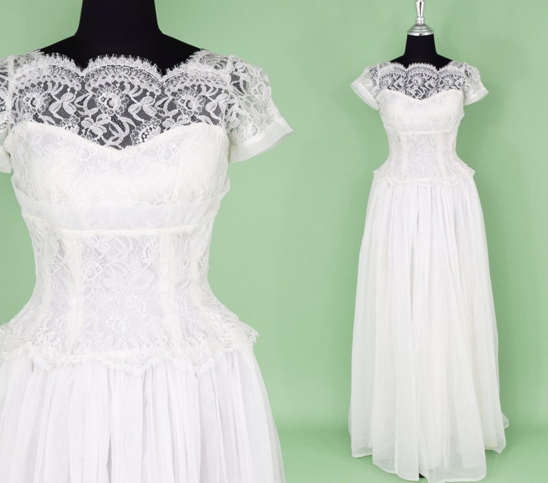 Puede incluir: Un vestido de novia vintage blanco con un corpi&ntilde;o de encaje y una falda completa. El vestido tiene mangas cortas y un escote redondo.