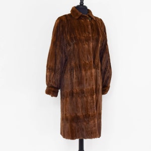 May include: A long brown fur coat with a collar and button closure.