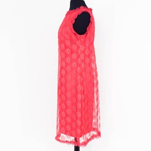 May include: A coral pink sleeveless dress with a floral pattern and lace trim. The dress is on a mannequin.