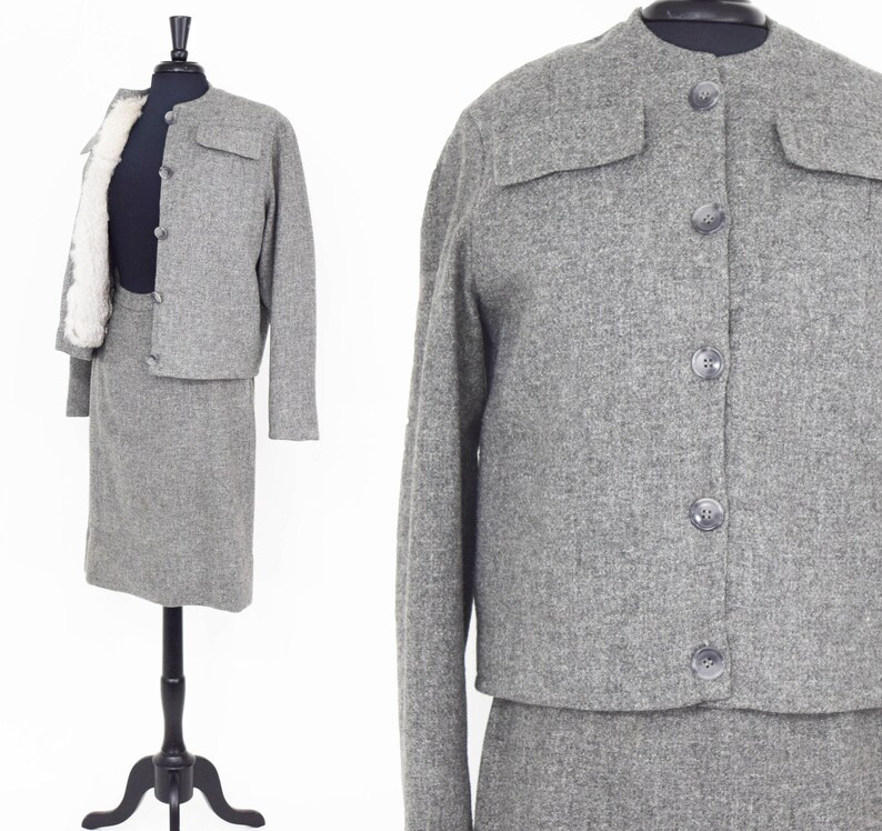 May include: A gray tweed skirt suit with a button-up jacket and a matching skirt. The jacket has two flap pockets on the front and the skirt is knee-length.