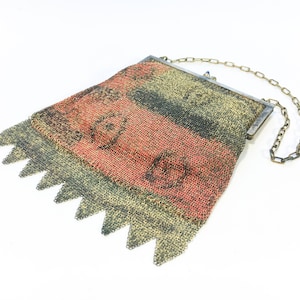 K&ouml;nnte beinhalten: Eine Vintage-Kettengewebetasche mit einer silbernen Kette und einem rot-schwarzen Design.