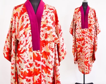 May include: A red silk kimono with a pink collar and a white and gold crane pattern. The kimono is displayed on a mannequin.