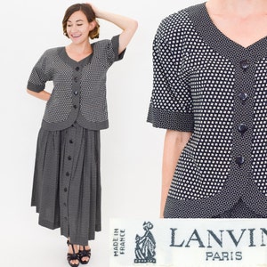 Puede incluir: Conjunto de falda y blusa con botones de estampado blanco y negro de Lanvin Paris. El conjunto incluye una blusa de manga corta y una falda hasta la rodilla con cierre de botones en la parte delantera.