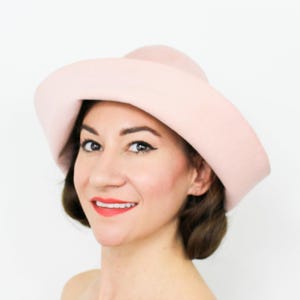 May include: A pink felt hat with a wide brim and a rounded crown.