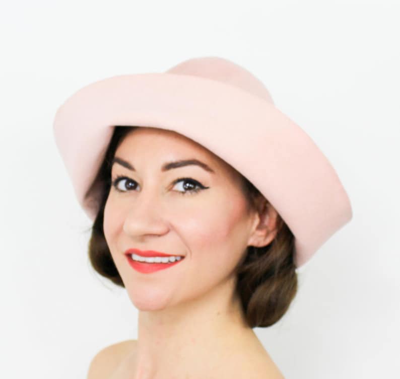 May include: A pink felt hat with a wide brim and a rounded crown.