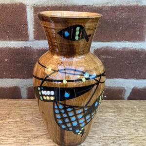 May include: A brown ceramic vase with a geometric design featuring blue, yellow and black fish.