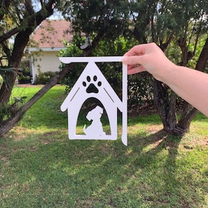 May include: White wooden dog house silhouette with a paw print on the roof and a small dog silhouette inside. The house is attached to a metal bracket.