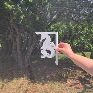 May include: White wooden bracket shaped like a seahorse. The bracket is designed to be mounted on a wall.