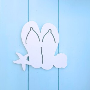 May include: White wooden cutout of a pair of flip flops with a starfish on a light blue background.