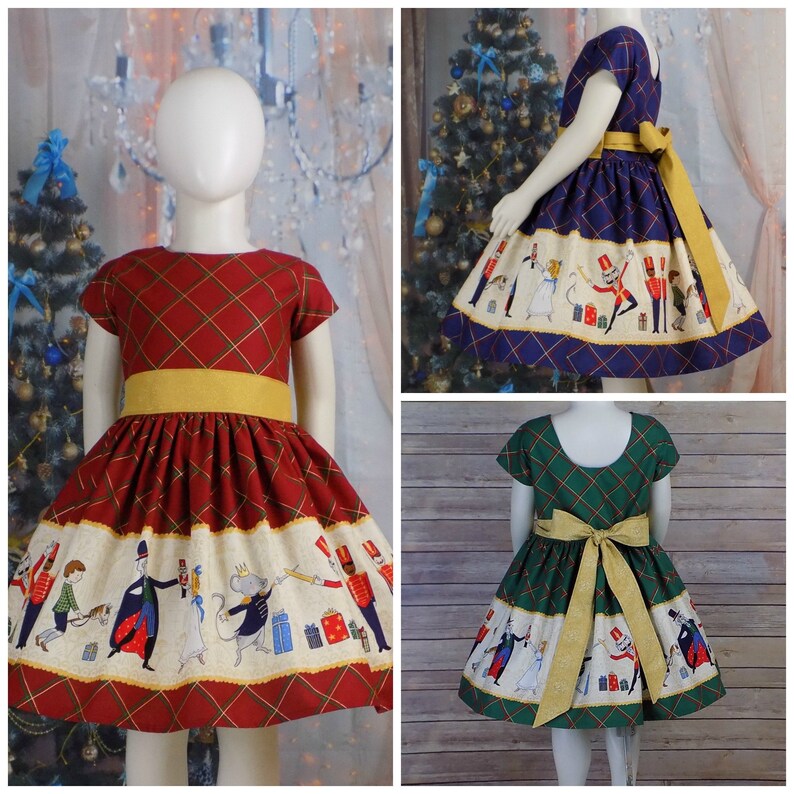 May include: Three girls' dresses with a Nutcracker theme. The dresses are red, blue, and green plaid with a white band featuring a Nutcracker scene. The dresses have yellow sashes.