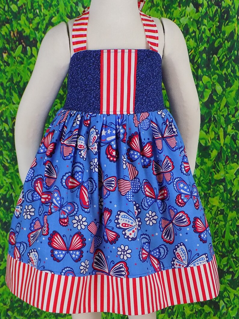 May include: A blue and red sleeveless dress with a butterfly print. The dress has a red, white, and blue striped bodice and hem.