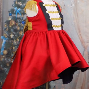 May include: A red and black dress with gold trim and buttons. The dress has a full skirt and a high neckline. It is a costume for a Nutcracker.