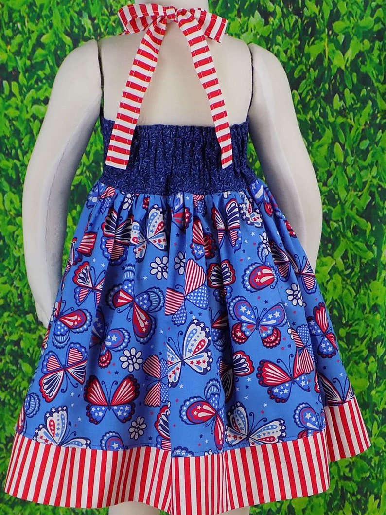 May include: A blue and red sleeveless dress with a halter top and a butterfly print. The dress has a red, white, and blue striped trim.