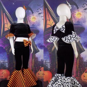 Pu&ograve; includere: Un costume di Halloween in velluto nero per un bambino. Il costume comprende un top corto nero con ali di pipistrello, pantaloni neri con strisce arancioni e nere e una gonna con stampa di pipistrelli in bianco e nero.