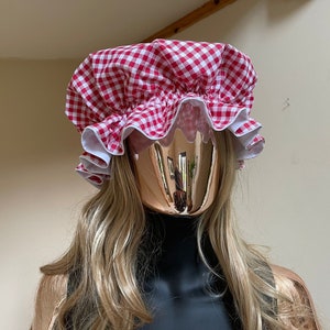 Könnte beinhalten: Eine Duschhaube aus rotem und weißem Gingham-Stoff mit einem Rüschenrand.