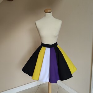 May include: A knee-length skirt featuring a flared silhouette and a wide black waistband. The skirt is constructed from vertical panels in alternating colors of black, yellow, white, and purple, creating a vibrant, multi-colored striped pattern.