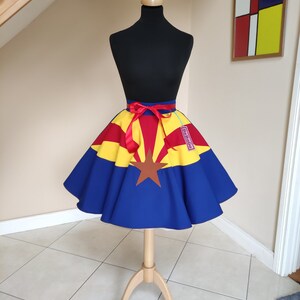 May include: A blue, yellow and red circle skirt with a red ribbon and a star in the centre. The skirt is on a mannequin and has a tag that says "BeBop."