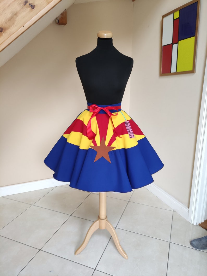 May include: A blue, yellow and red circle skirt with a red ribbon and a star in the centre. The skirt is on a mannequin and has a tag that says "BeBop."
