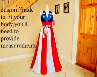 May include: A custom-made dress on a mannequin, featuring a halter top with blue and white stars, a red midsection, and a long skirt with red and white stripes. The text on the image says "custom made to fit your body, you'll need to provide measurements."