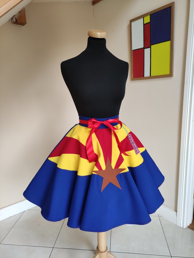 May include: A blue, yellow and red circle skirt with the Arizona state flag design. The skirt has a red ribbon tied at the waist and a "Retago" tag.