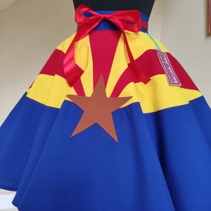 May include: A blue, red and yellow skirt with a brown star in the centre. The skirt is a circle skirt with a red ribbon tied around the waist. The tag on the skirt says "BeBopGo".