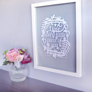 Puede incluir: Arte de papel cortado en blanco enmarcado en un marco blanco. El arte presenta un dise&ntilde;o floral con el texto "Sarah y Nicholas Te amo cada pedacito de ti 10 de noviembre de 2015".