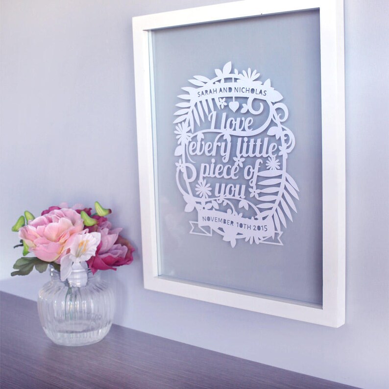 Puede incluir: Arte de papel cortado en blanco enmarcado en un marco blanco. El arte presenta un dise&ntilde;o floral con el texto "Sarah y Nicholas Te amo cada pedacito de ti 10 de noviembre de 2015".