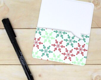 May include: A white card with a snowflake pattern on the back. The card is folded in half and has a blank front.