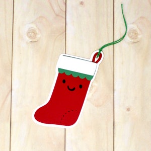 May include: A red and white Christmas stocking with a green trim and a smiling face. The stocking has a hole at the top for hanging.
