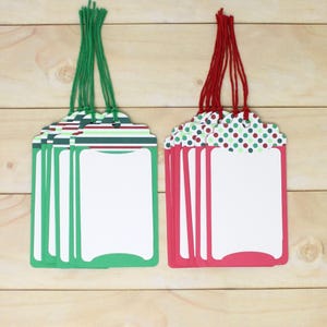 May include: A set of rectangular paper gift tags with rounded corners and white centres. One group features green striped tops with green strings, while the other group features red and green polka dot tops with red strings for attachment.
