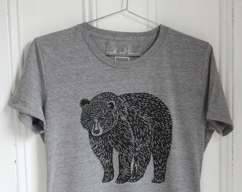 May include: A heather grey t-shirt with a black and white illustration of a bear. The shirt has the text "hearth and harbor" printed on the tag.