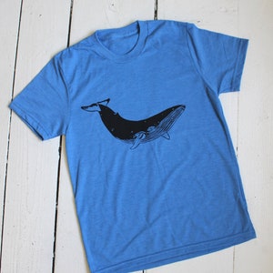 May include: A blue t-shirt with a black silhouette of a whale printed on the front.