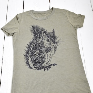 May include: A green t-shirt with a black and white illustration of a squirrel holding a nut. The text "earth and" is visible on the shirt.