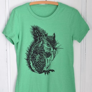 May include: A green t-shirt with a black and white illustration of a squirrel holding a nut in its mouth.