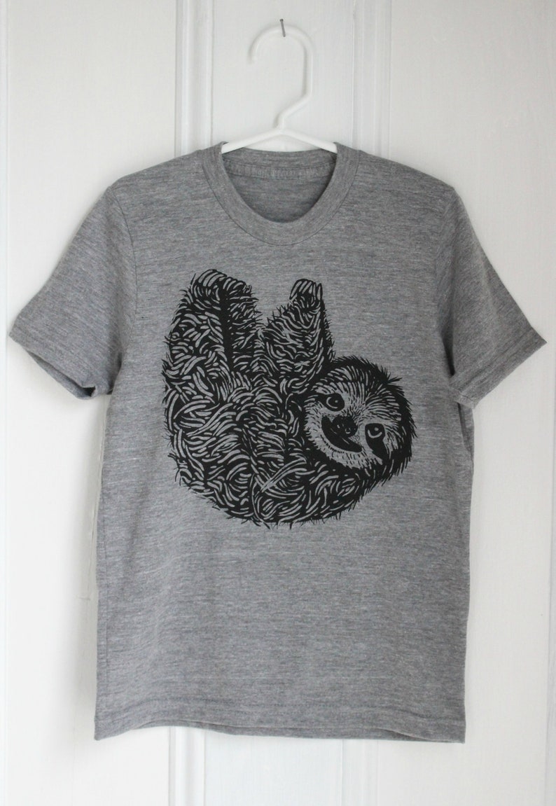 May include: A heather grey t-shirt with a black and white illustration of a sloth hanging upside down.