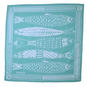 May include: A turquoise blue bandana with a white border and five white fish designs. The fish are all different and have various patterns. The bandana has the text "SHEARTHING HARROW" in white.