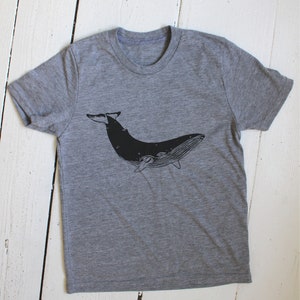 May include: A heather grey t-shirt with a black silhouette of a whale printed on the front.