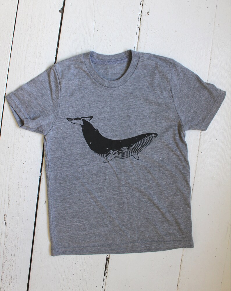 May include: A heather grey t-shirt with a black silhouette of a whale printed on the front.