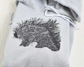 Könnte beinhalten: Ein grauer Kapuzenpullover mit einer schwarz-weißen Illustration eines Stachelschweins auf der Vorderseite.