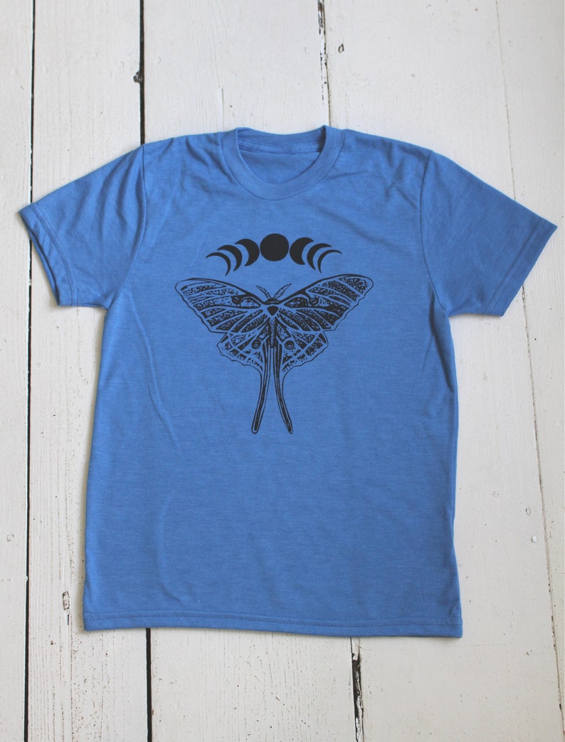 May include: A blue t-shirt with a black and white moth design and a crescent moon graphic.
