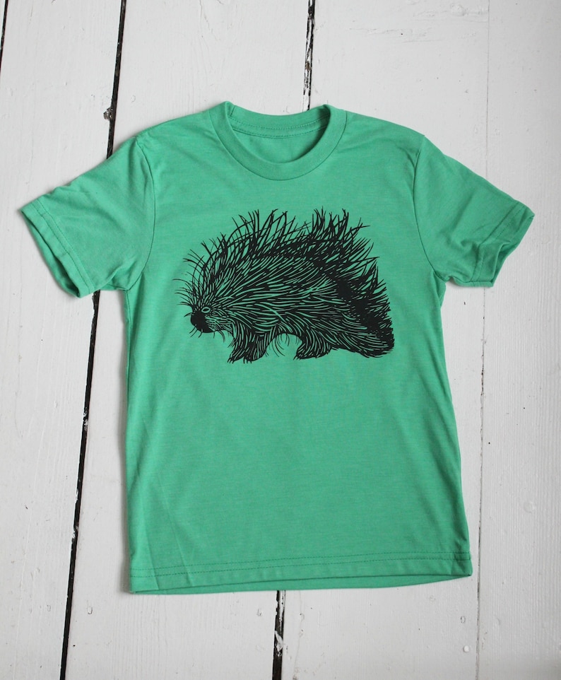 May include: A green t-shirt with a black and white illustration of a porcupine.
