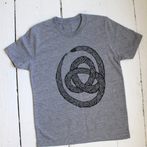 May include: A gray t-shirt with a black and white graphic print of a snake coiled in a circle. The snake is patterned with geometric shapes.