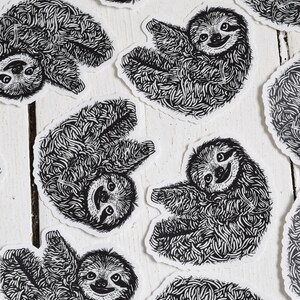 May include: A set of nine black and white sloth stickers. Each sticker features a different pose of a sloth with a detailed, intricate design.