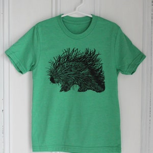 May include: A green t-shirt with a black and white illustration of a porcupine.
